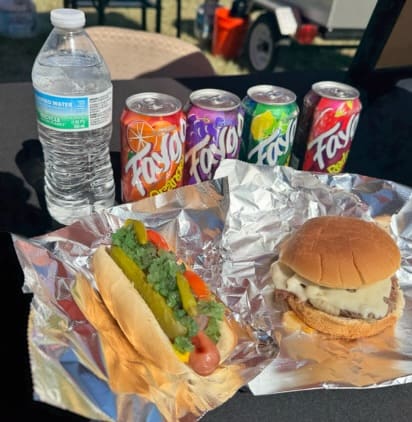 A table topped with foil covered sandwiches and fries.